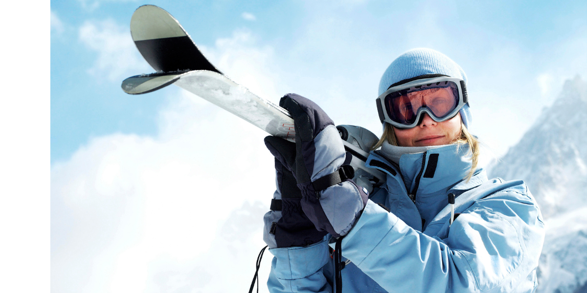 Outdoor Skiing Jacket Person wearing a blue outdoor skiing jacket holding skis in snowy mountains